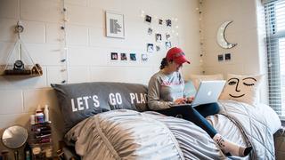 student sitting on her bed inside her dorm at villiger hall, one of saint joseph's university's first-year dormitory