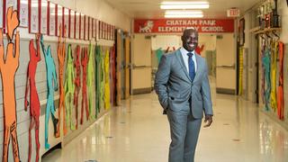 jabari whitehead, ed.d., wearing a suit and standing inside an elementary school hallway