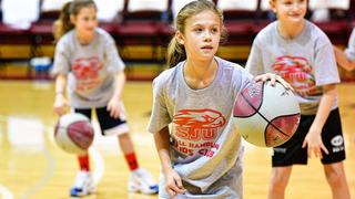 Three little girls in a gym, dribbling basketballs