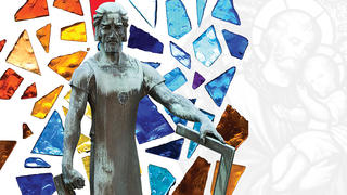 statue of saint joseph with stained glass behind it