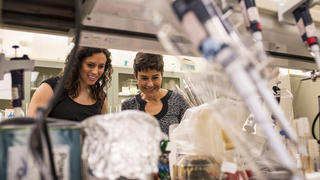 Two female scientists are surrounded by lab equipment.