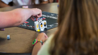 A hand reaches for a game piece on a board game.