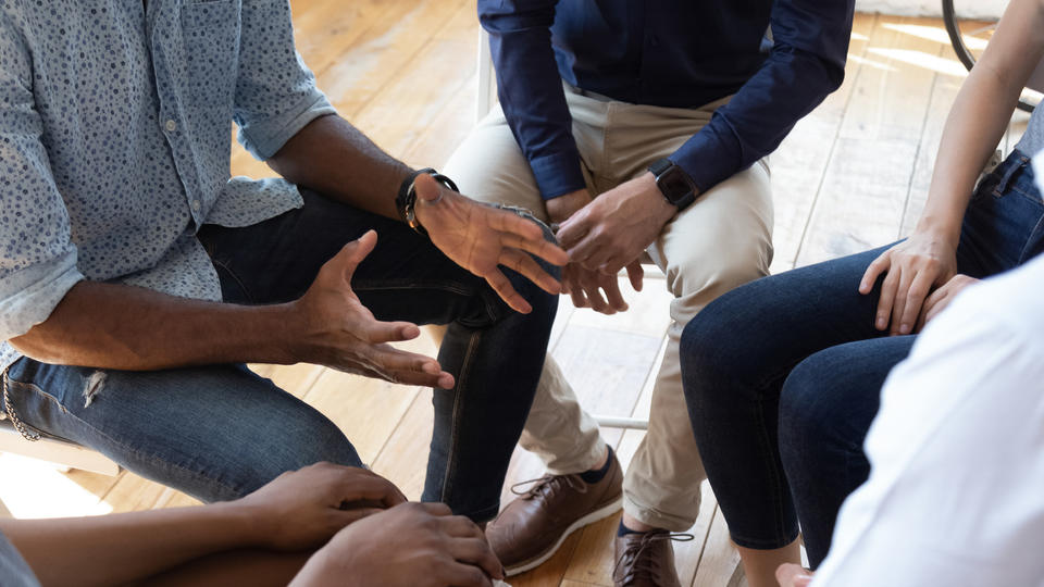 A closeup of hands in a circle, perhaps in a recovery group meeting