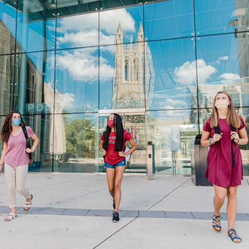 Saint Joseph's University's Barbelin Hall reflecting of Drexel Library's window while students walk with masks practicing safe distancing