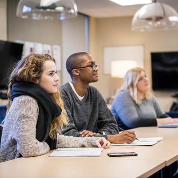 3 students looking at professor in the communication lab