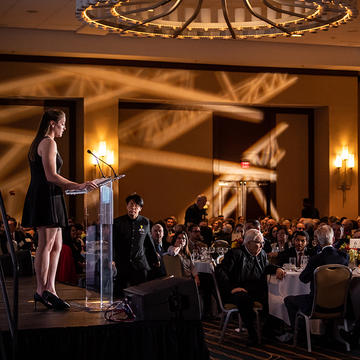 Woman stands at podium at Leadership Awards dinner.