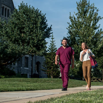 A man in scrubs walking with a woman on campus