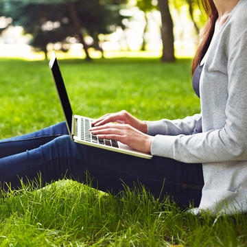 Student studying outside with a laptop in their lap