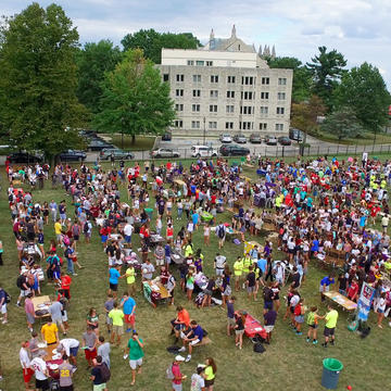 A filed is filled with tables of information with lots of students walking around
