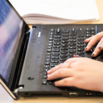 student typing on a laptop