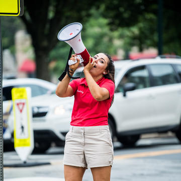A woman holds a megaphone to welcome new students.