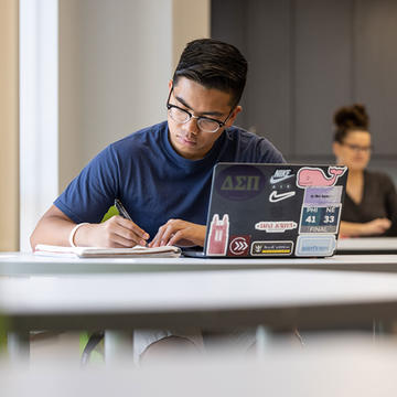 Student writing in a notebook in a classroom