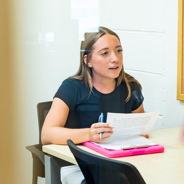 female student interviewing someone in a classroom setting