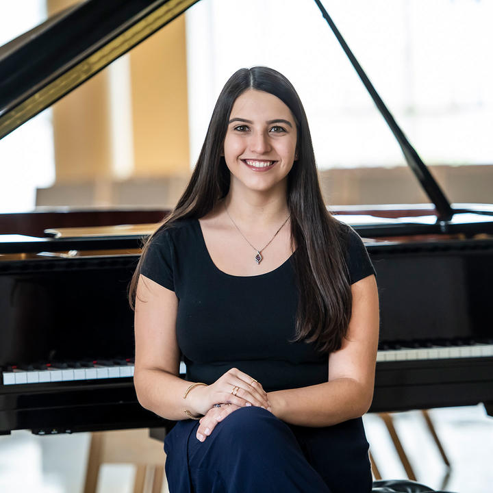 Olivia Centonza sitting in front of a piano