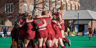 Field hockey players jump in an embrace after a win