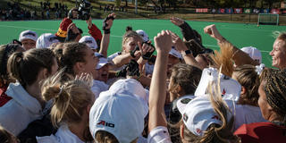 Saint Joseph's University Field Hockey team celebrating with a group hi-five on the field.