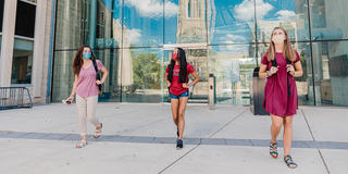 Saint Joseph's University students walking on campus next to the library wearing masks and practicing safe distancing