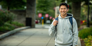 a student wearing a hoodie and walking on saint joseph's campus