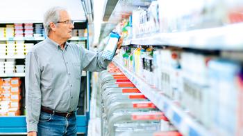 Older male examining a carton of milk at the grocery store