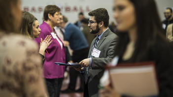 Students and employers talk in the aisle at the career fair