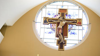 A crucifix hanging in front of a stained glass window