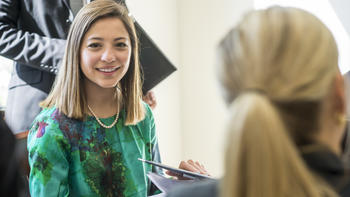 A woman in a green shirt smiles at the camera