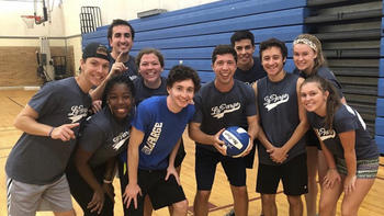 a group of students pose with a volleyball on a court