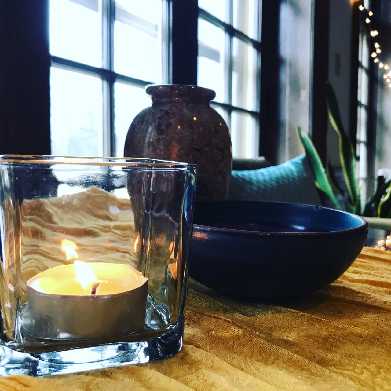 A lit candle sitting on a table with flowers