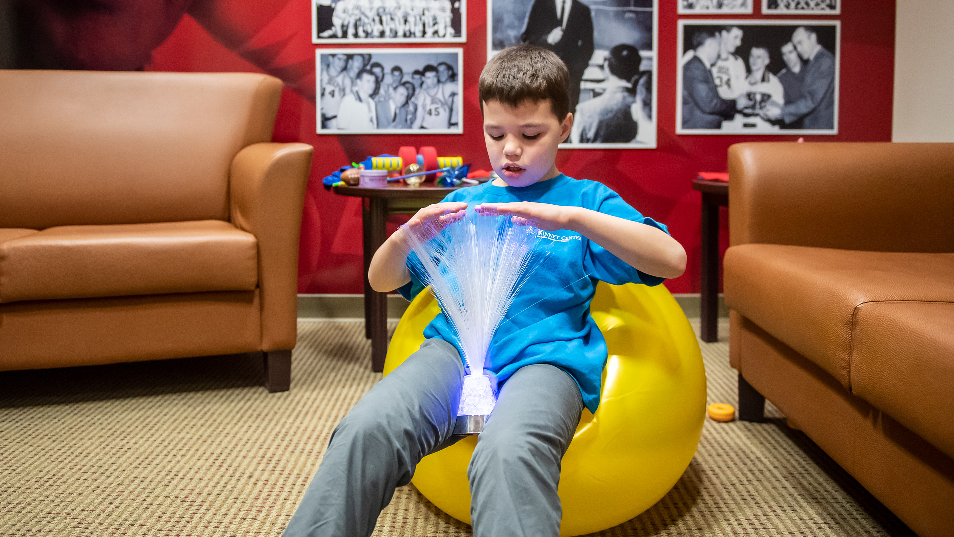 Young student sitting on yellow yoga ball playing with a sensory-friendly toy