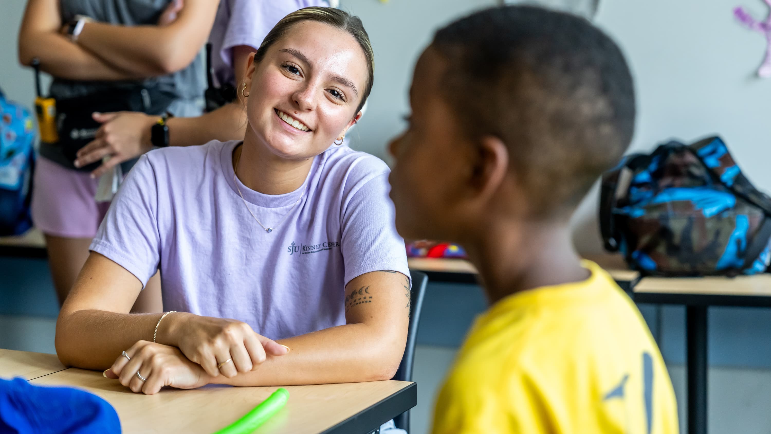 female student teacher sitting with Kinney student in classroom