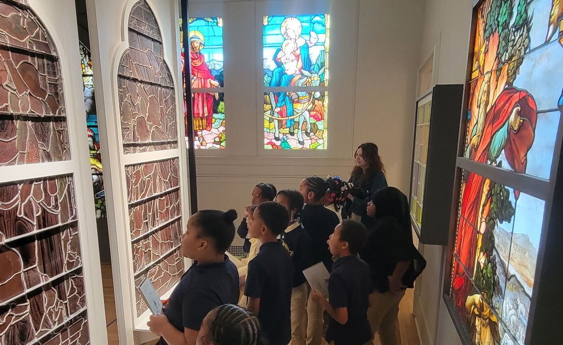 Students in the stained glass gallery with an educator.