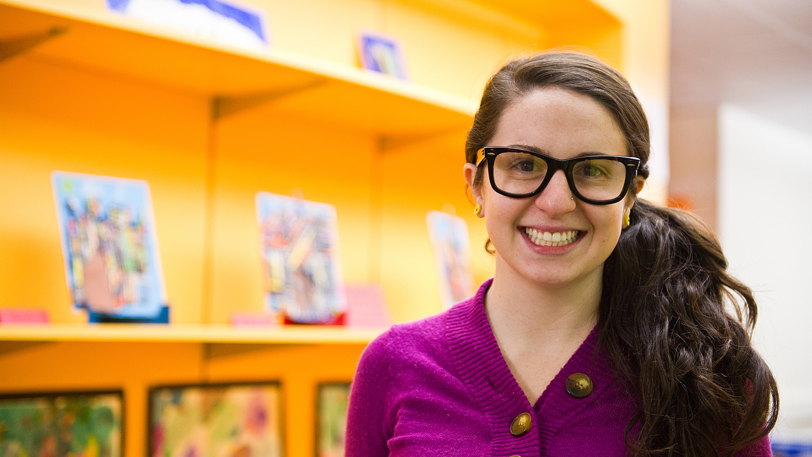 female teacher standing near rows of books