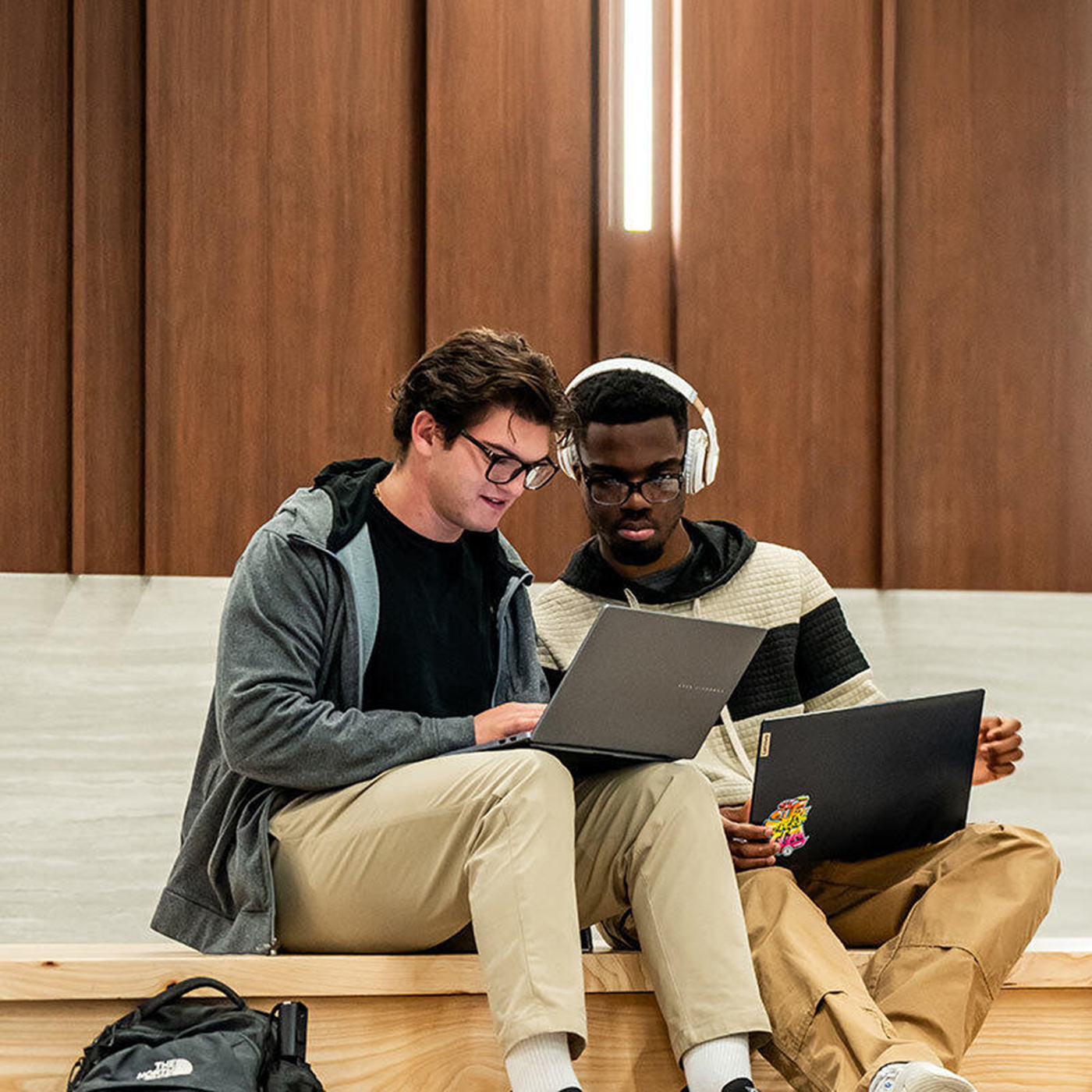 Two students looking at their laptops