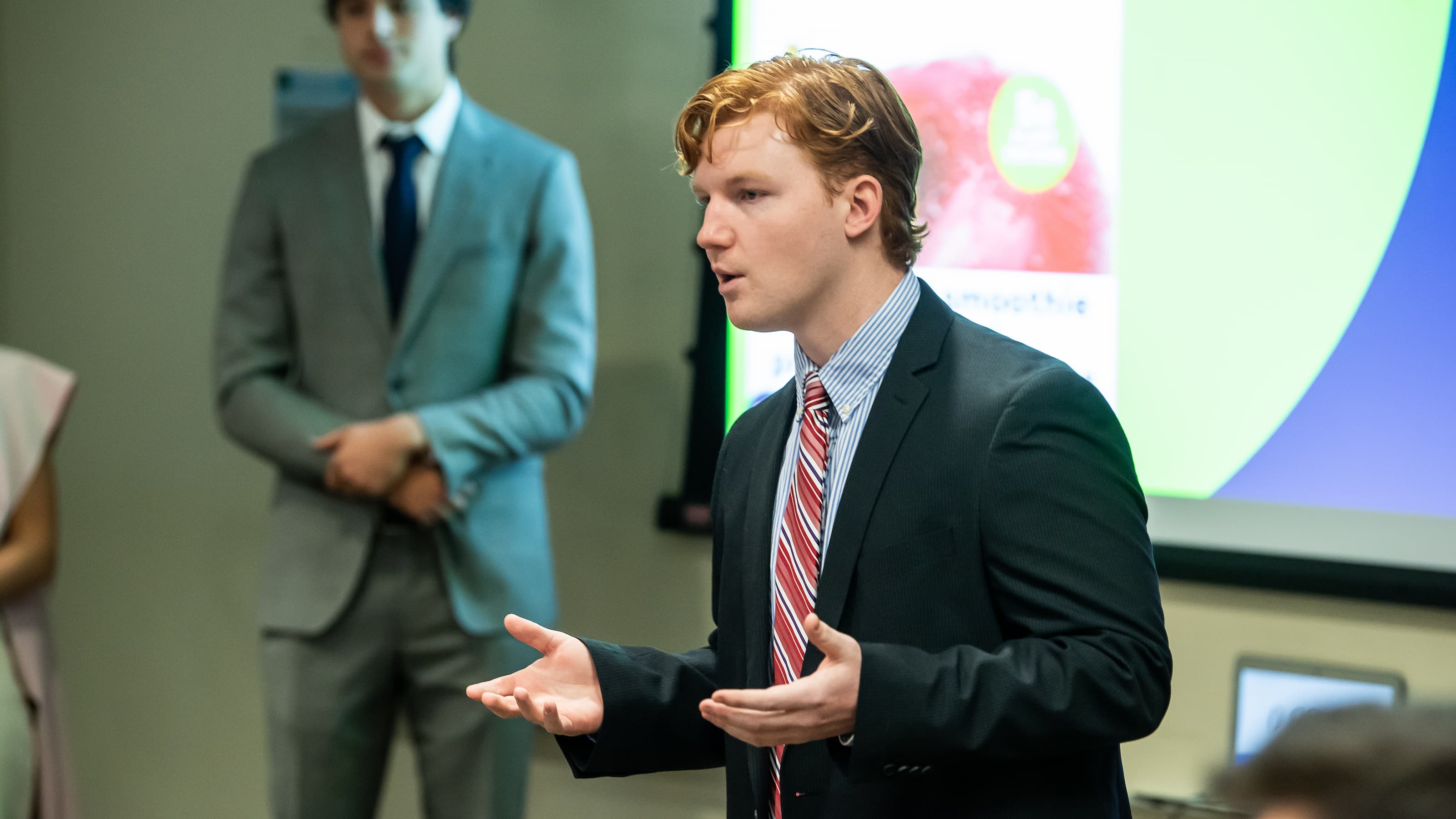 A student in a suit and tie giving a presentation. 