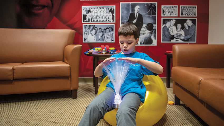 boy sitting on bean bag playing with fiber optic light-up wand