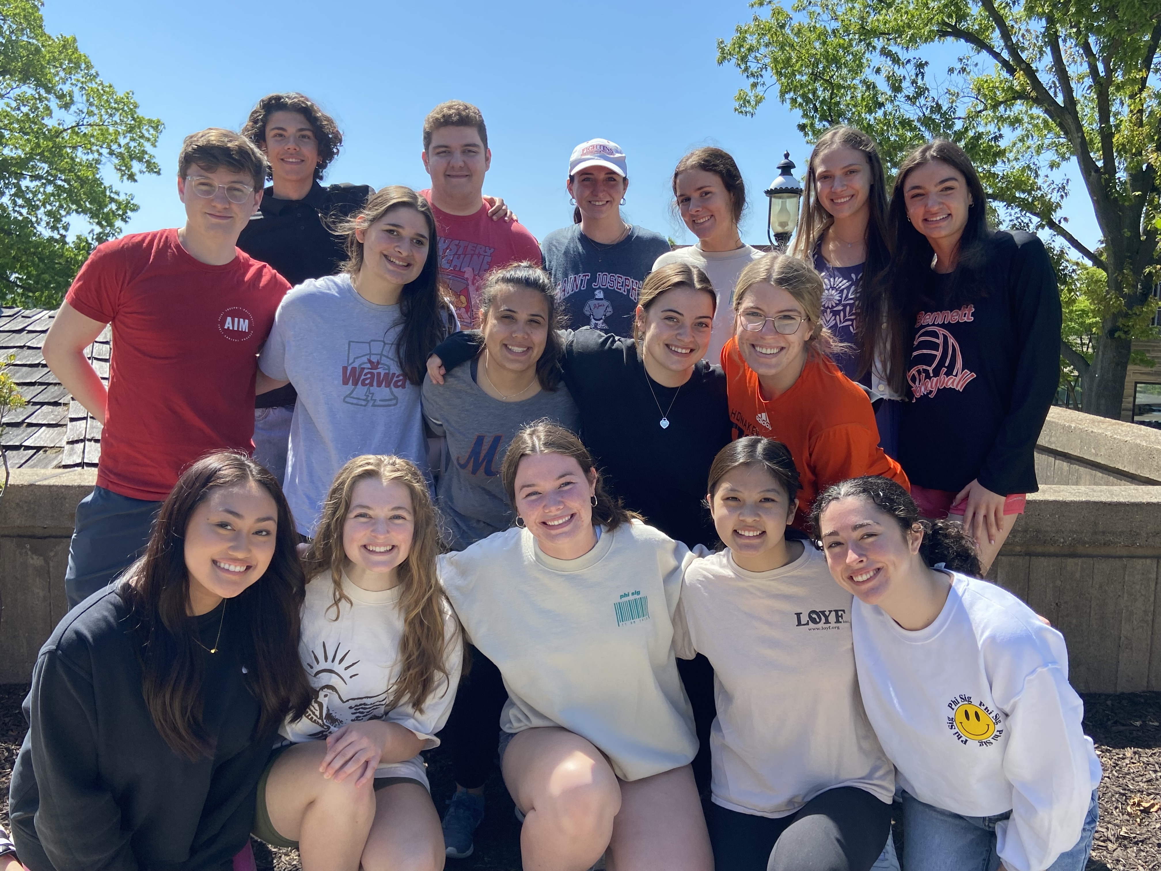 A group of students standing together, outside smiling.