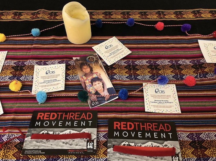 A table with a colorful tablecloth, candles, and pamphlets on it