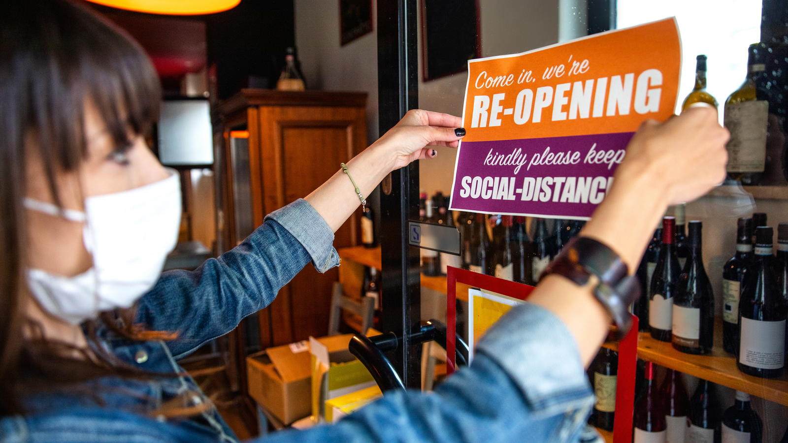 Woman hanging a "we're reopening" sign