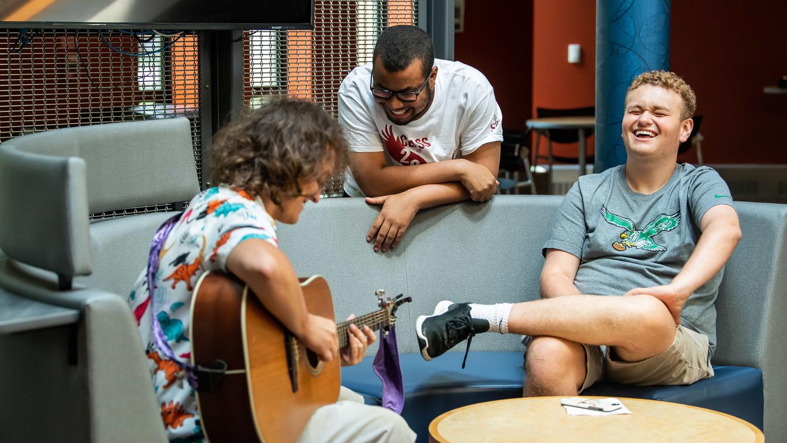 three students laughing and hanging out inside a residence hall