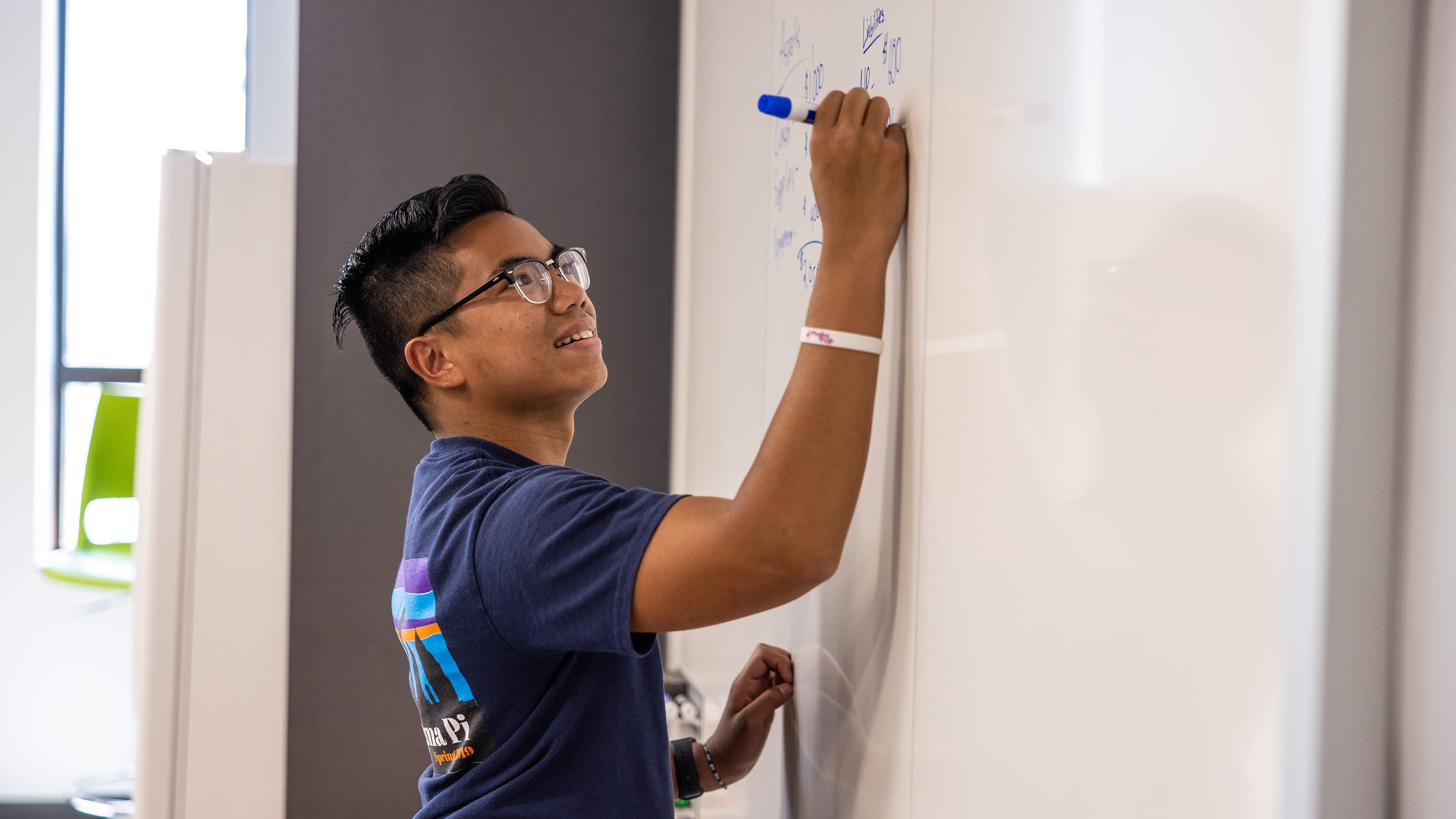 Male student writing on white board