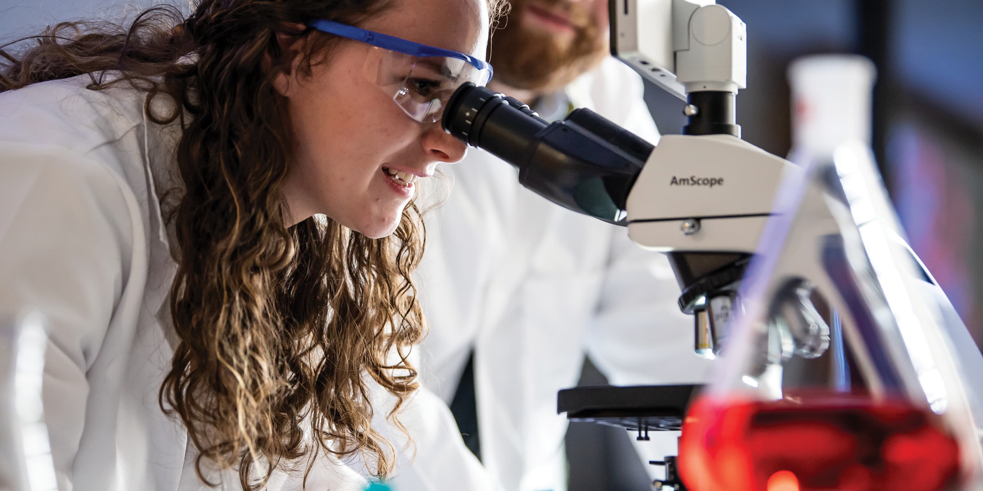 A pharmacology/toxicology student looking through a microscope