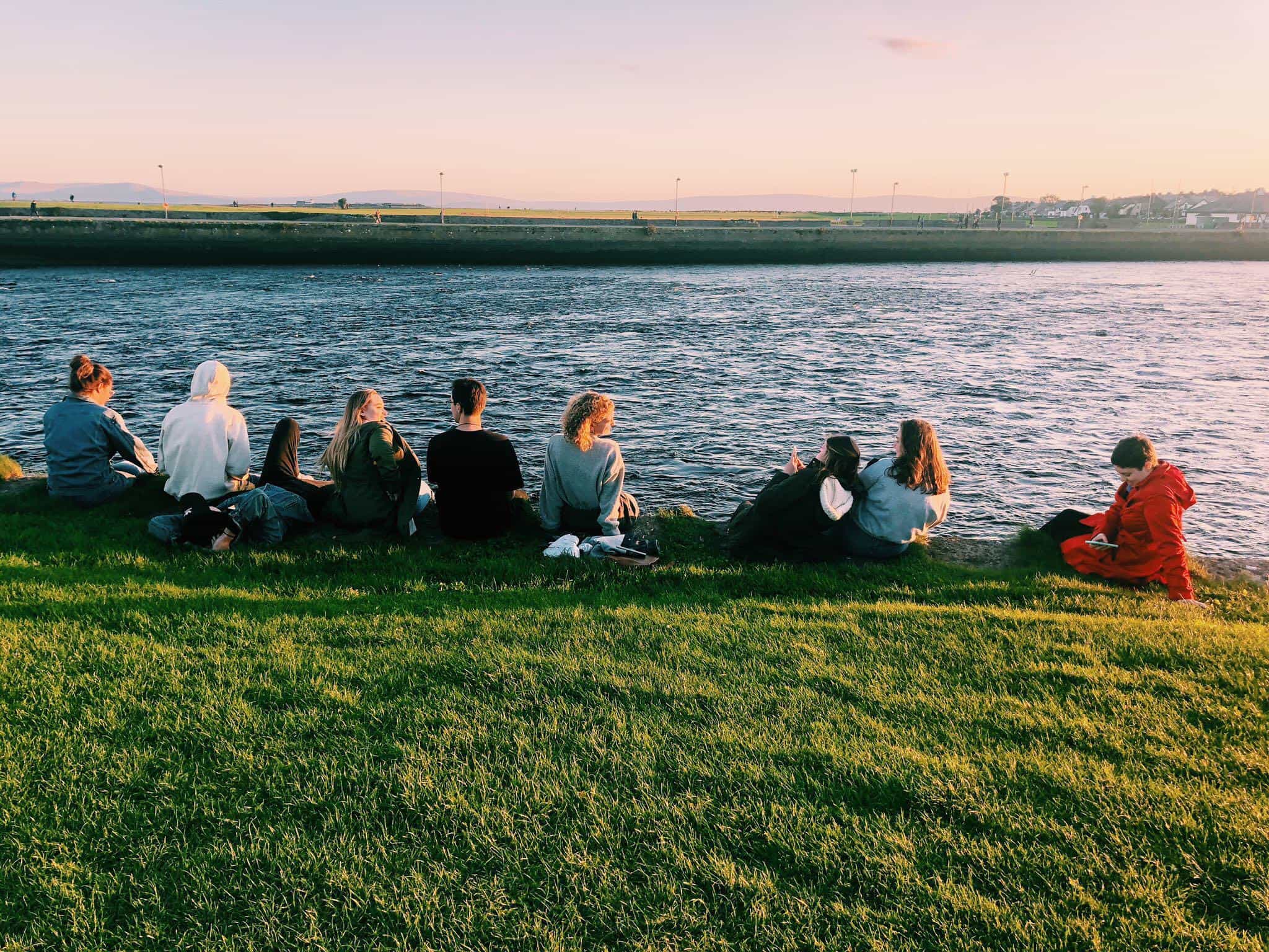 group of college students sitting by a lake in ireland