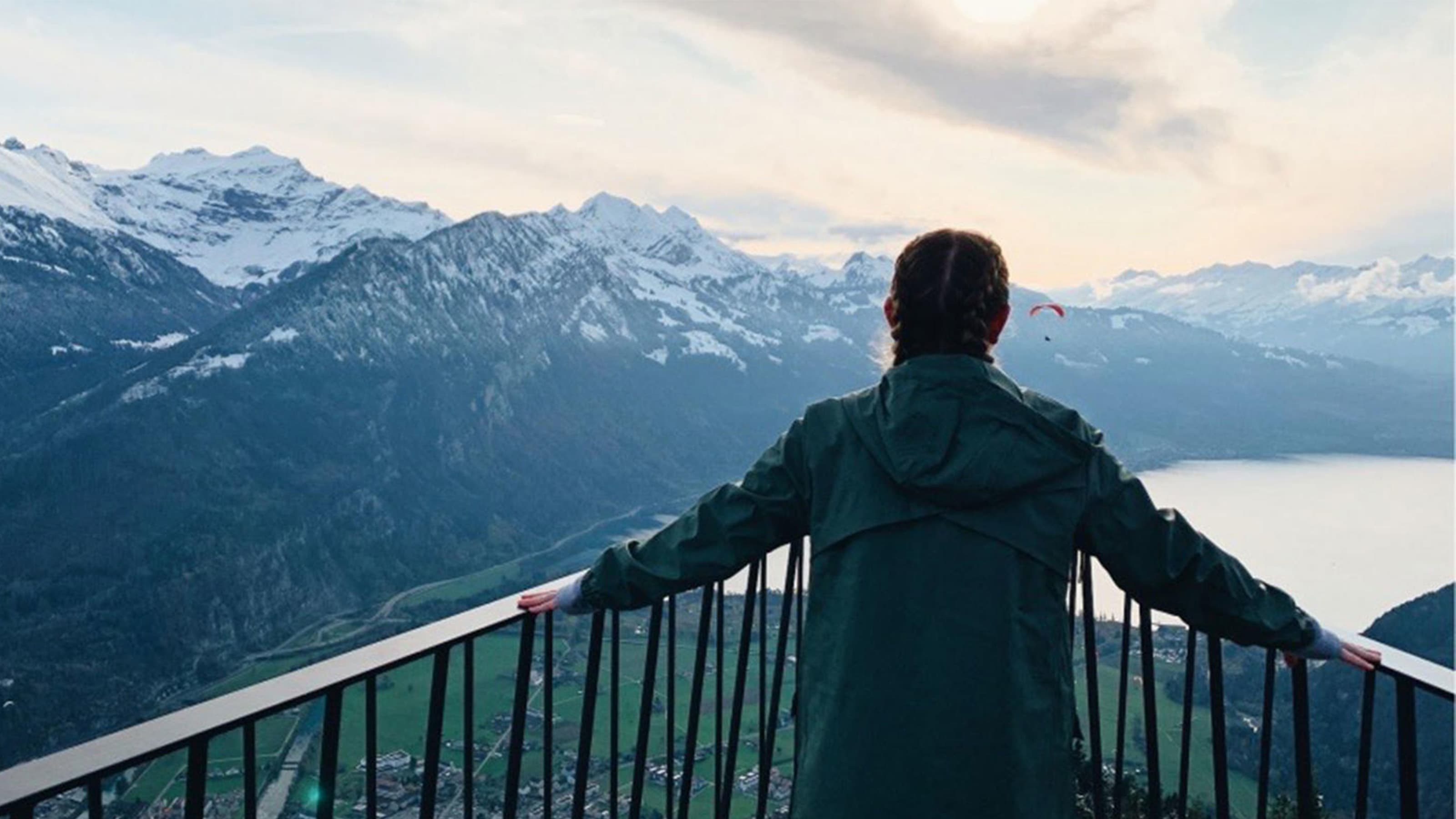 Student standing on balcony overlooking mountains and lake