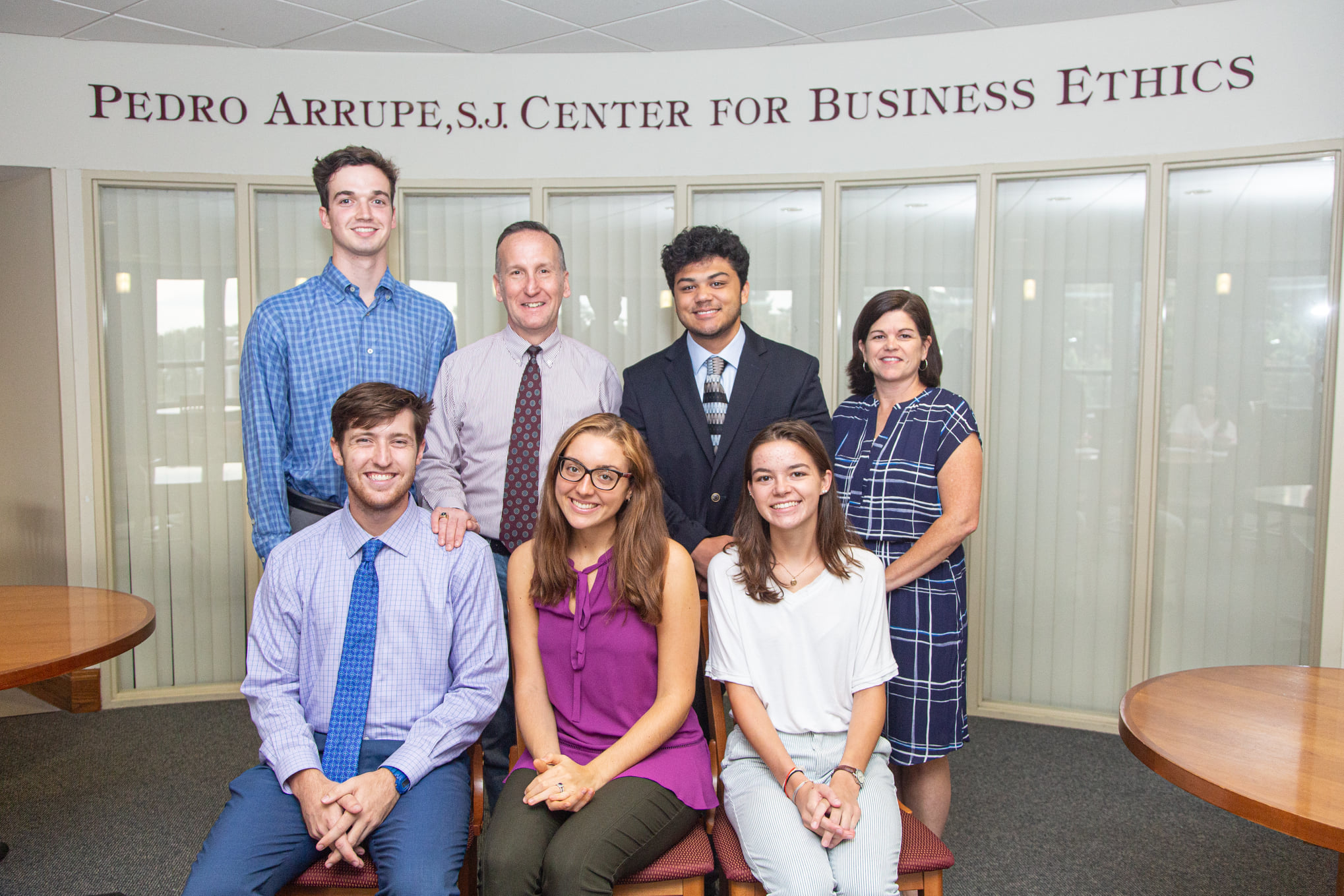 The student and faculty team from the Arrupe center pose in front of the sign.