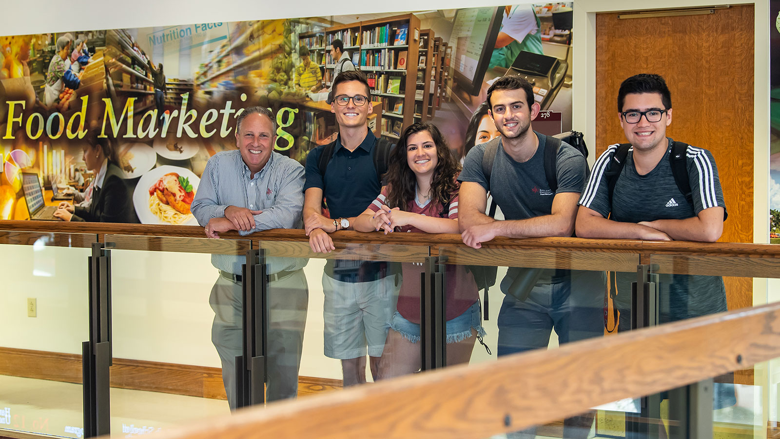 Students and professor standing in front of the food marketing mural