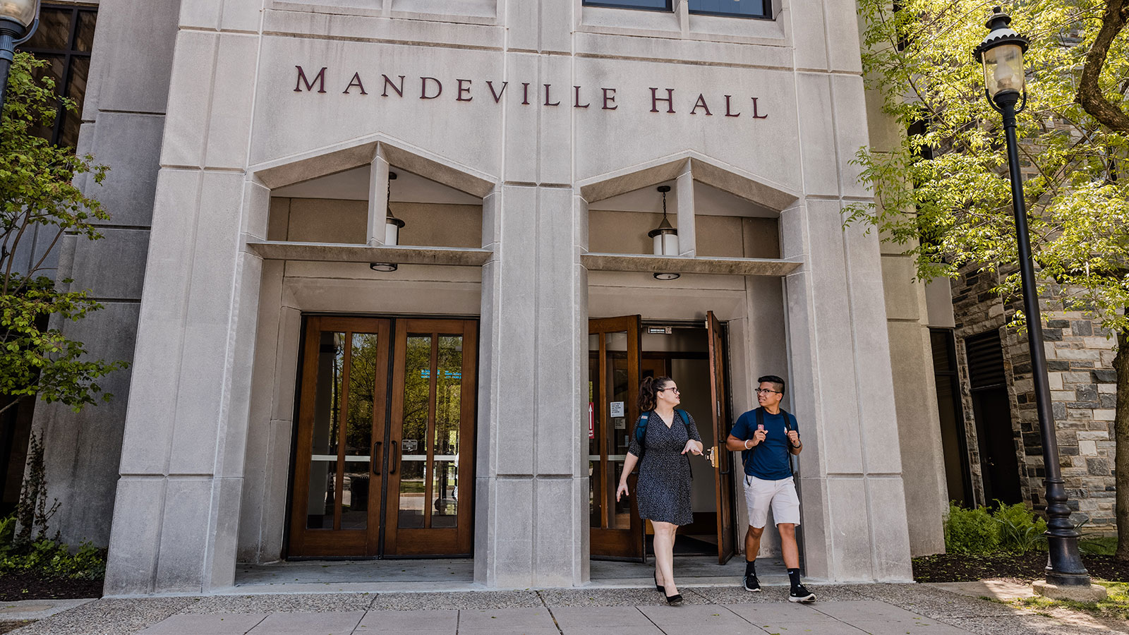 Two students walking outside of Mandeville Hall at Saint Joseph's University