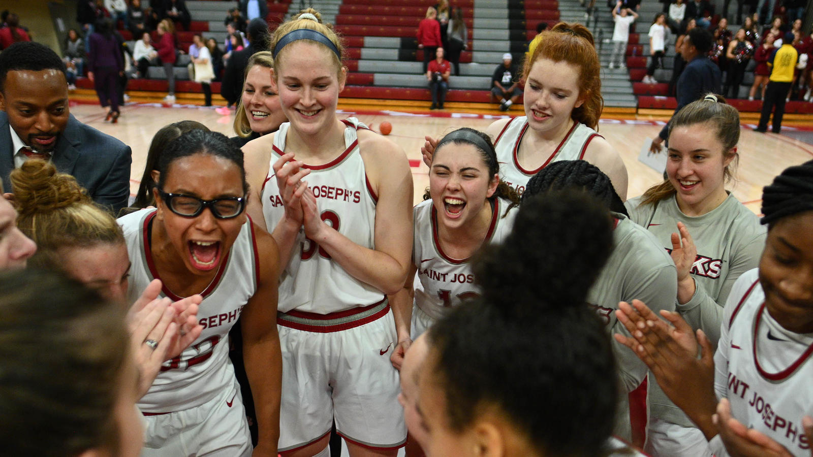 SJU women's basketball team gathered in a circle on the court