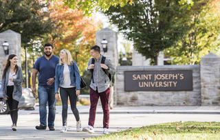 Students walking across City Ave. in fall at Saint Joseph's University