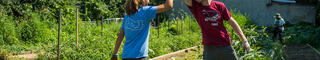 Students high five as the work in a garden