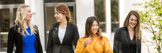 4 women smiling and talking outside on a sunny day